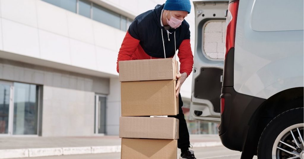 man getting boxes loaded in van for order dispatch
